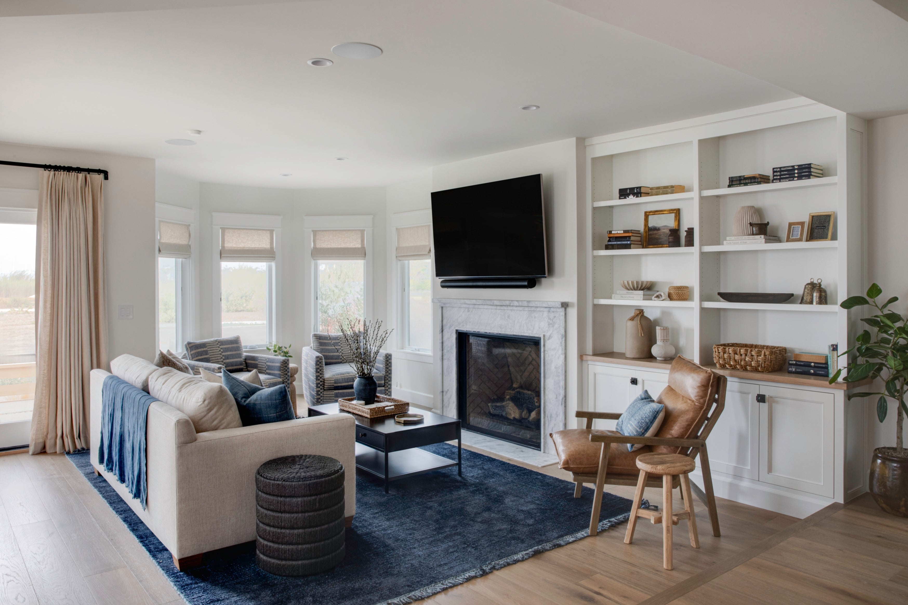 Waterfront living room in an Old Town Seal Beach ground-up build by B Farm Design, featuring a marble fireplace, custom white built-ins, and coastal transitional furnishings.