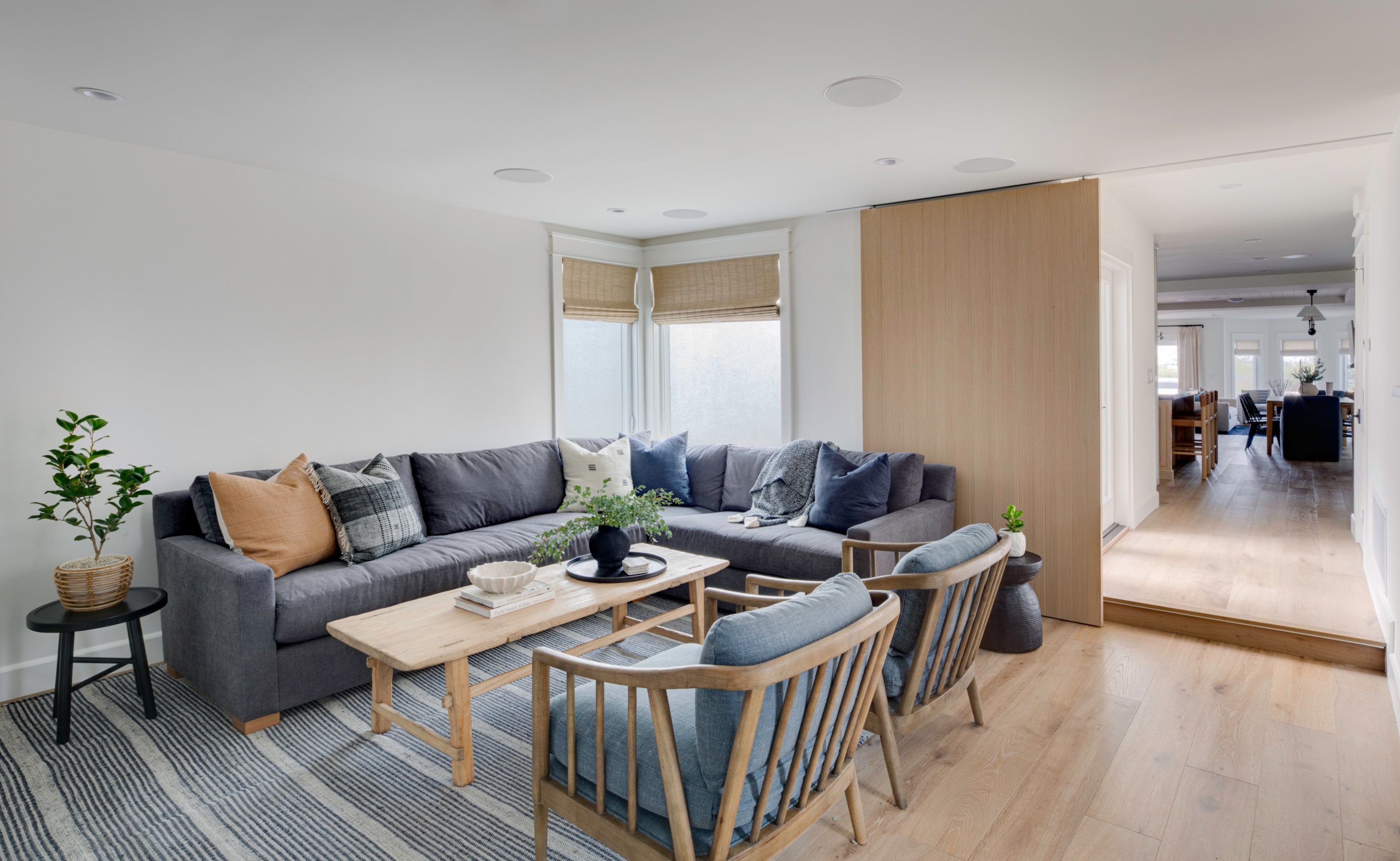Modern living room with gray sectional sofa, wooden coffee table, and armchairs.