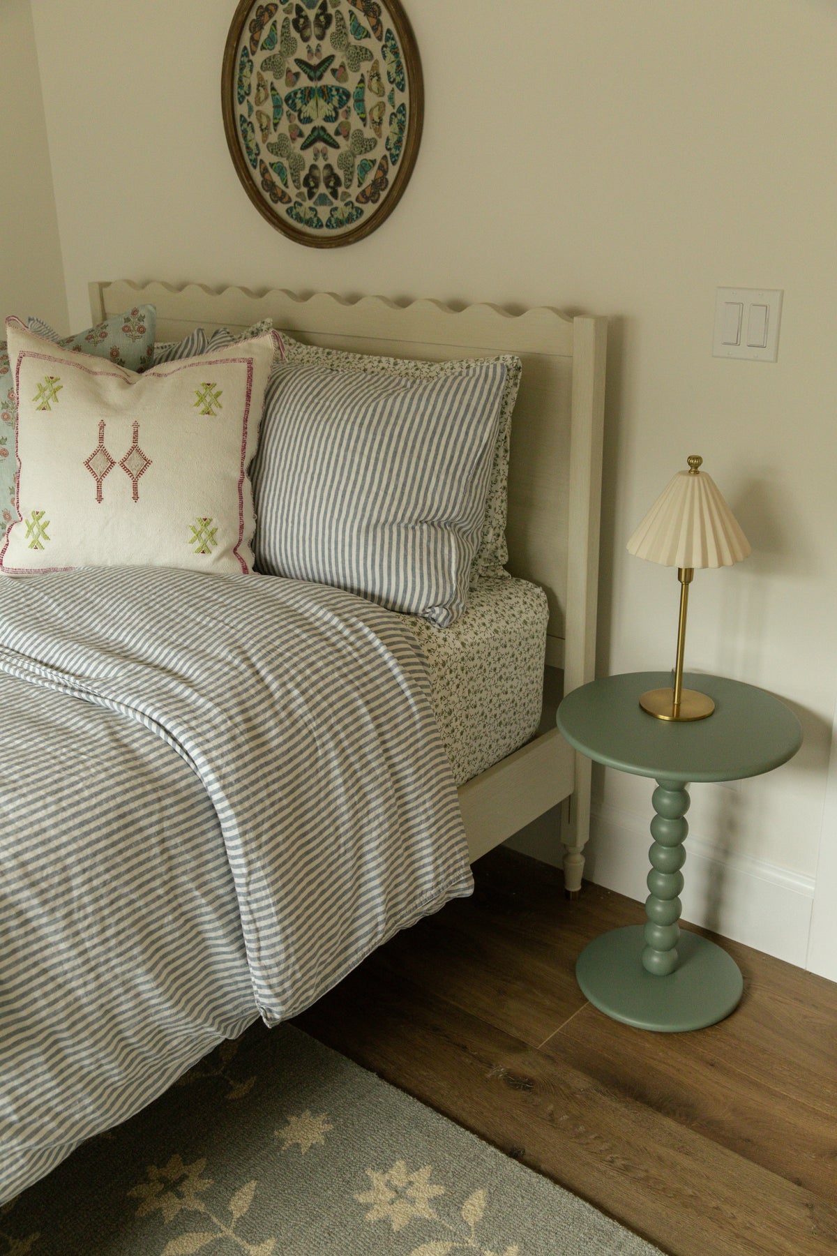 Charming craftsman guest bedroom design with a custom scalloped headboard, curated block-print textiles, and a bespoke painted spindle nightstand, designed for a quaint but high-end remodel.