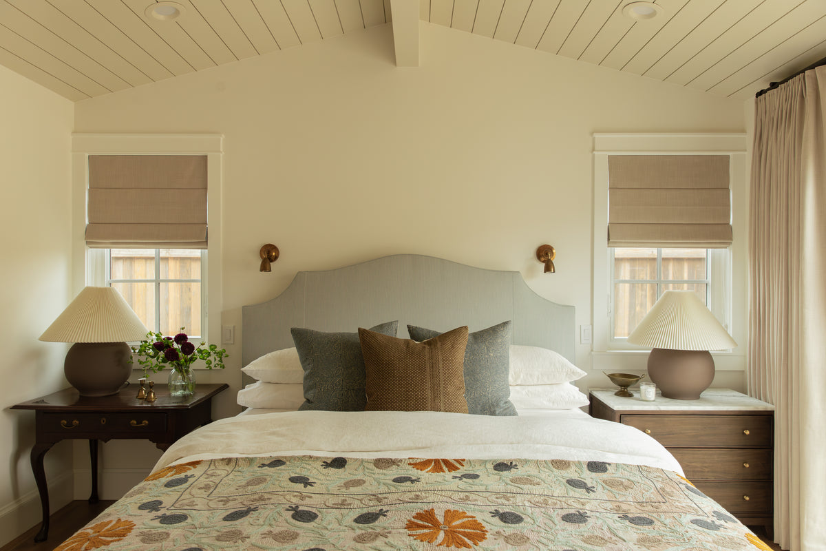 Craftsman primary bedroom with a blue striped arched headboard, vaulted panel calendar ceiling, matching bedside lamps, and patterned duvet cover.