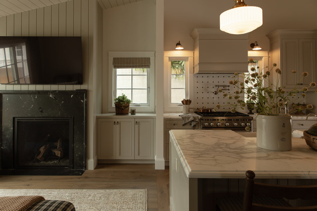 Open floor plan view transitioning from the living room fireplace area into the Craftsman kitchen island and range hood setup.