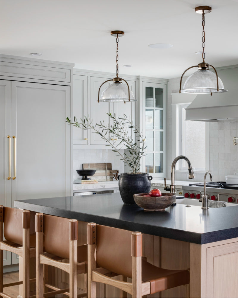 Modern kitchen with island, leather chairs, and antique brass fixtures.