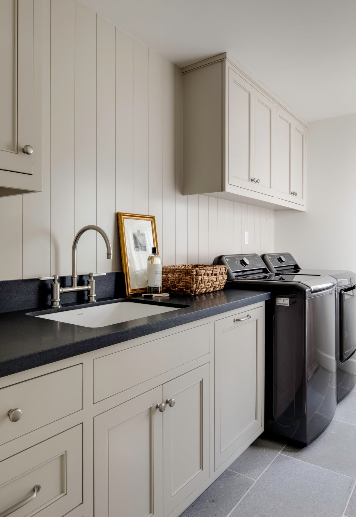 Transitional laundry room design showcasing sophisticated cabinetry, a vertical shiplap wall treatment, and durable dark countertops.