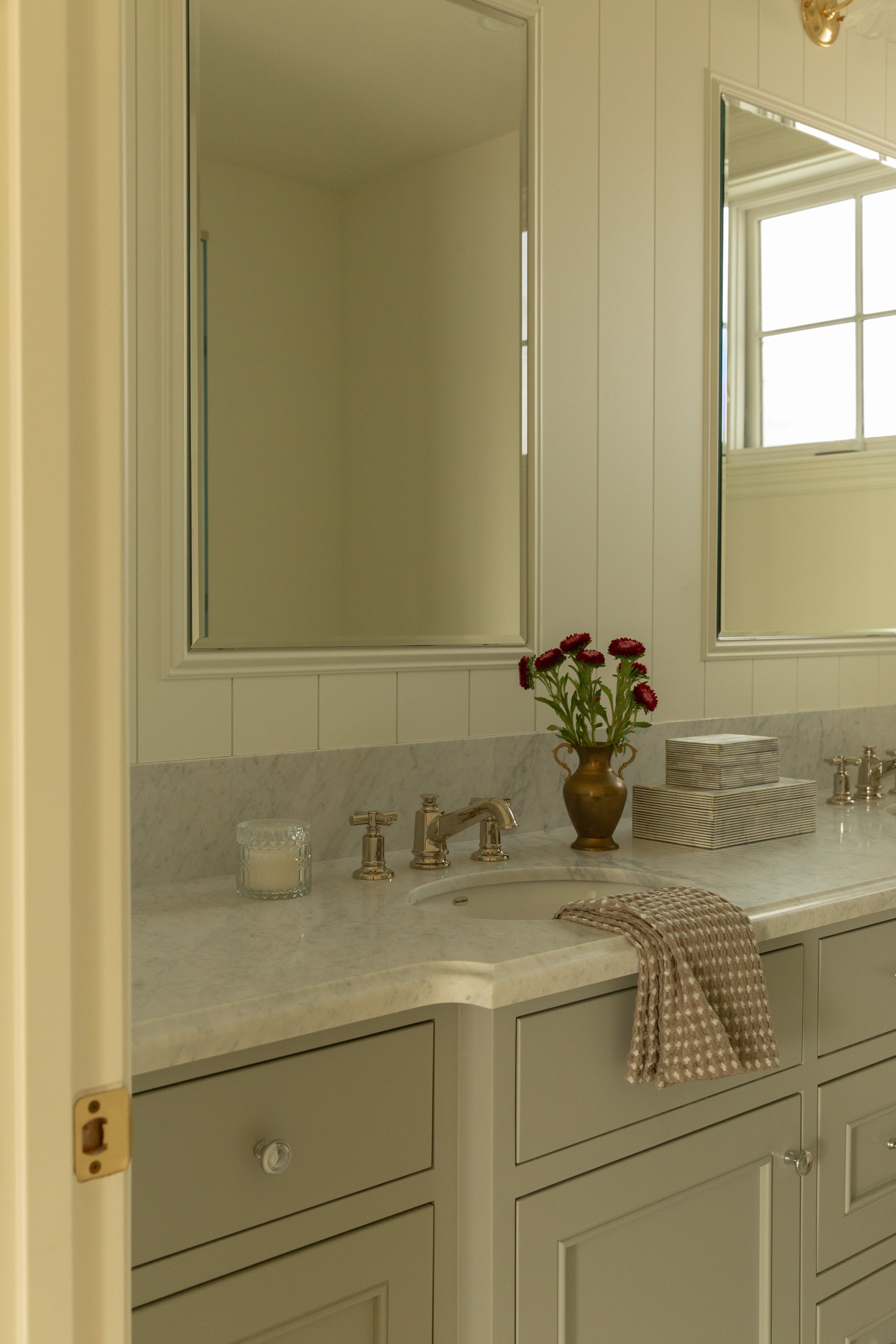 Light gray pigeon double vanity with a white marble countertop and silver fixtures set against a classic white paneled wall in an Orange County bathroom remodel.