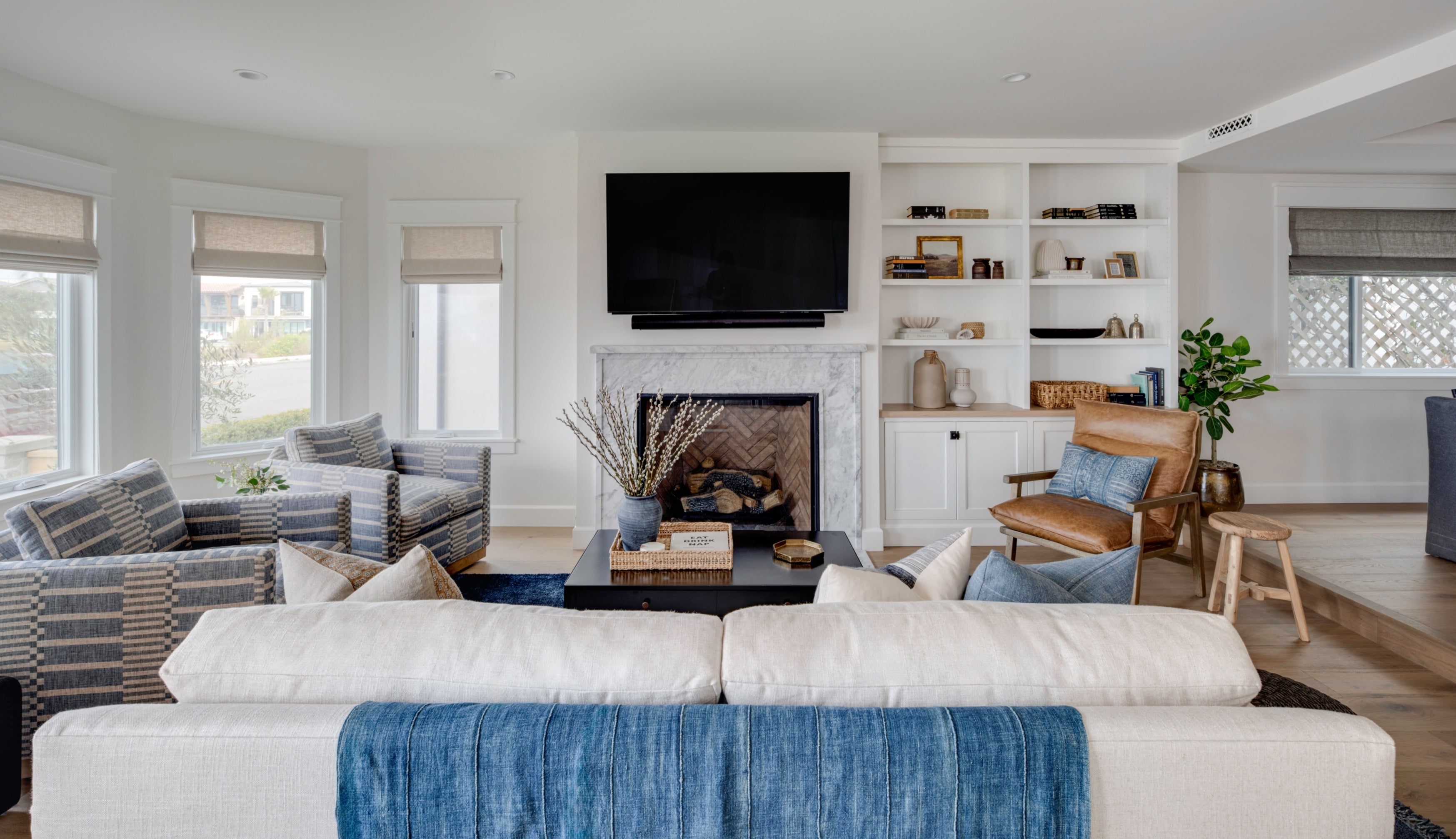 Living room in a Seal Beach custom home by B Farm Design featuring a marble fireplace, custom white built-in shelving, and transitional coastal furnishings.