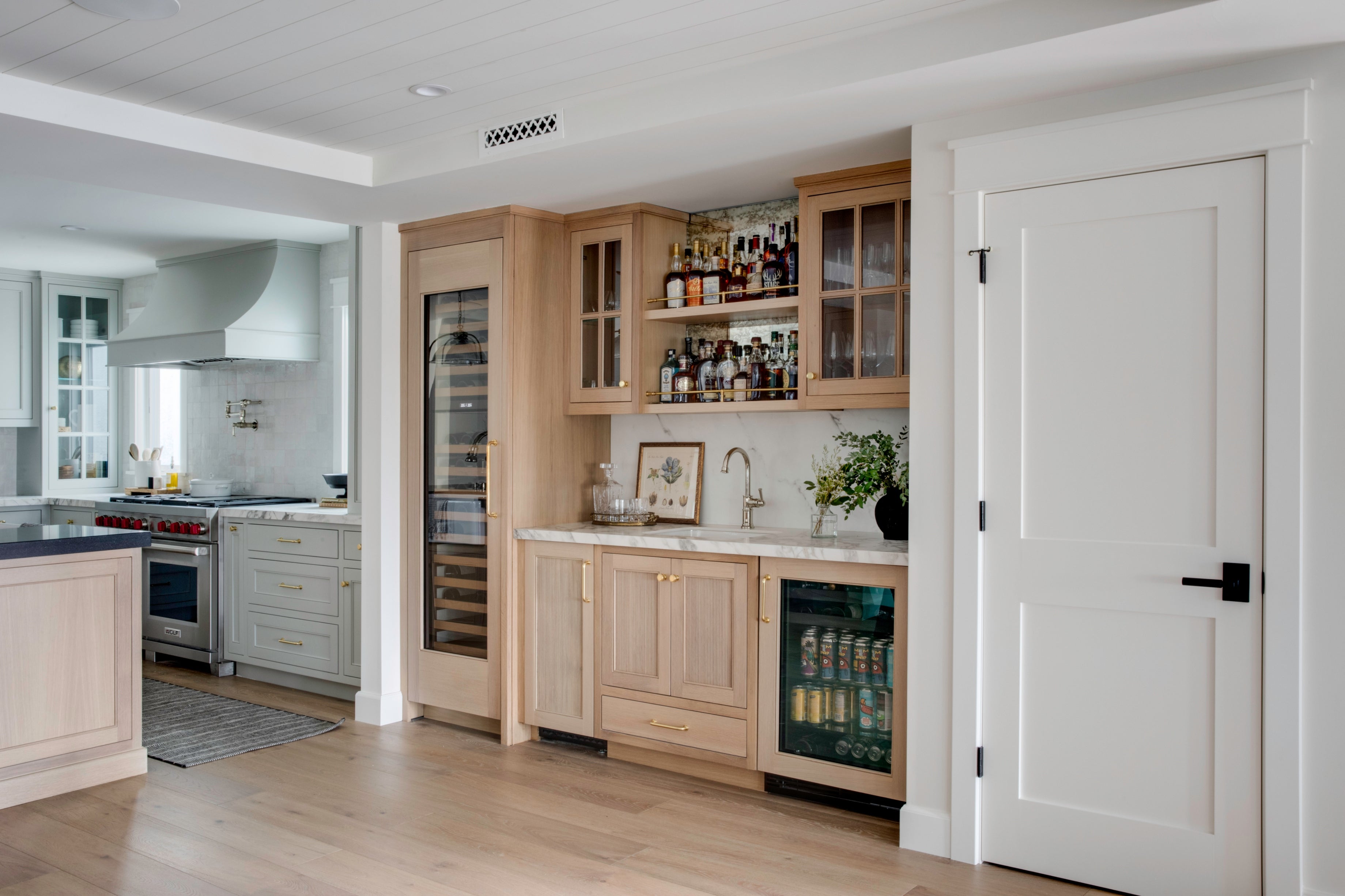 Luxury custom built-in bar by B Farm Design. Features fluted white oak cabinetry, wine glass display shelving, a full-size wine cooler, and integrated beverage fridge.