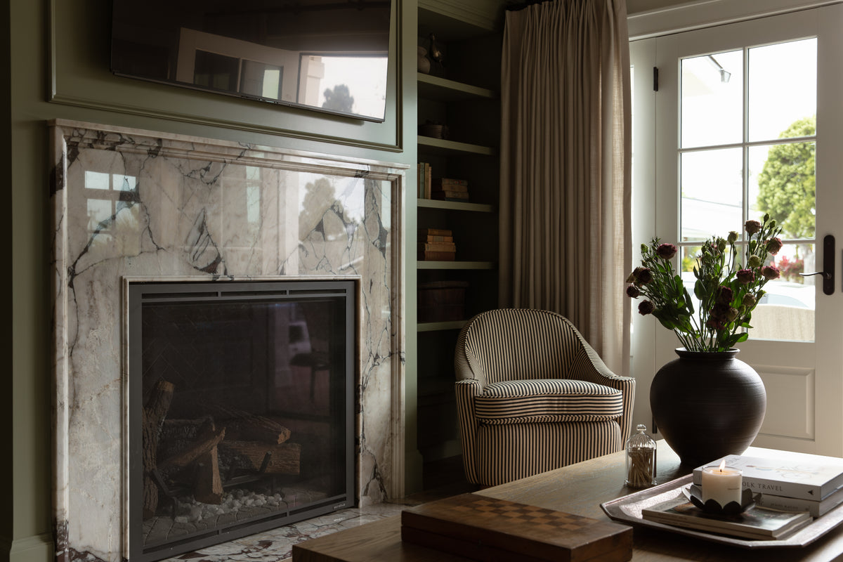 Full-scale residential remodel living room showcasing a marble fireplace, olive green paneling, built-in library shelves, and bespoke decor by Old Town Seal Beach interior designer. 