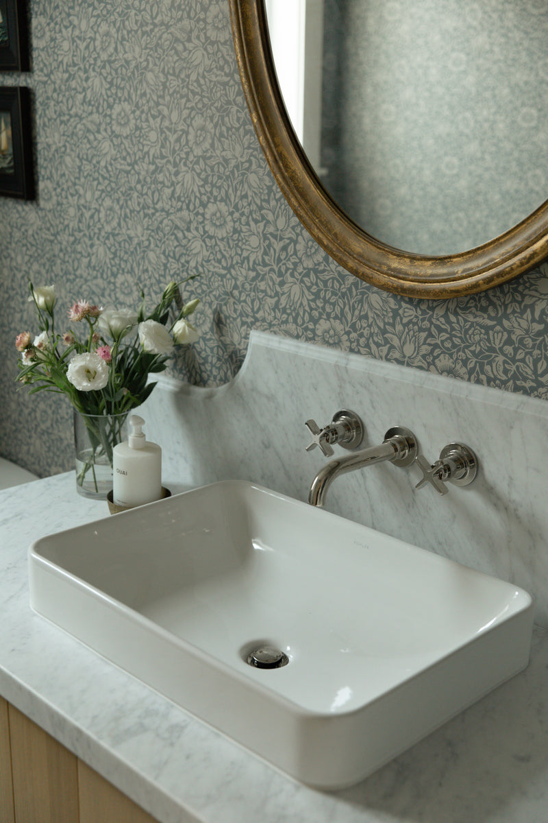 A sleek white rectangular vessel sink sitting on a custom marble countertop featuring an elegant, curved backsplash detail.