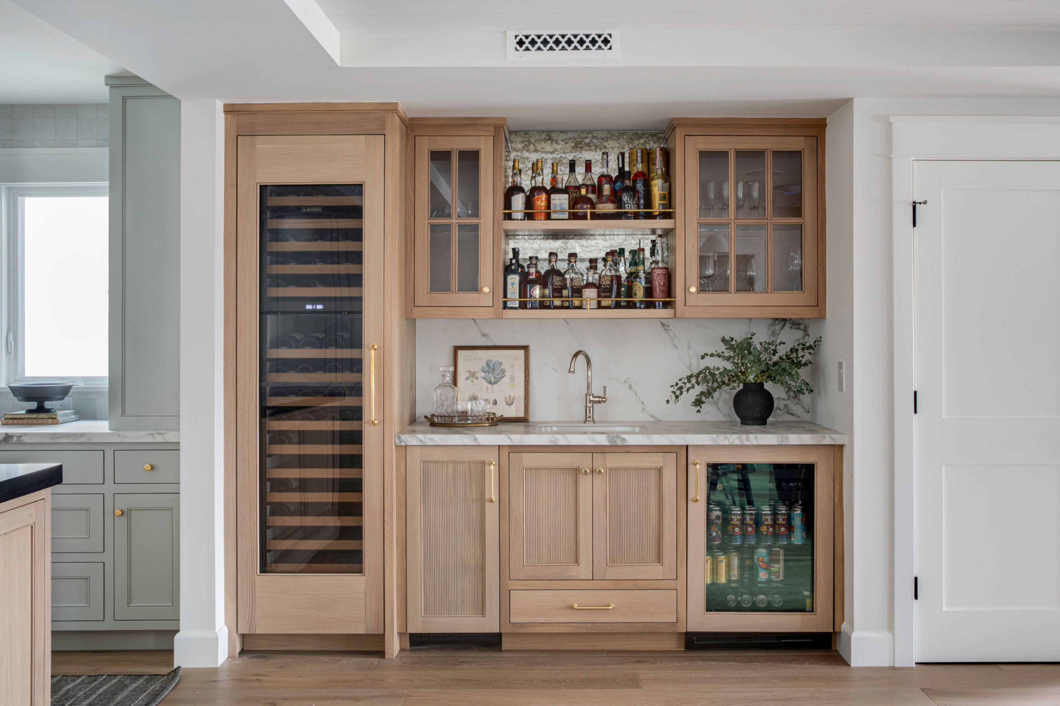 Custom built-in wet bar showcasing natural wood finishes, antique mirror backsplash, brass hardware, and dual integrated refrigerators for wine and beverages.